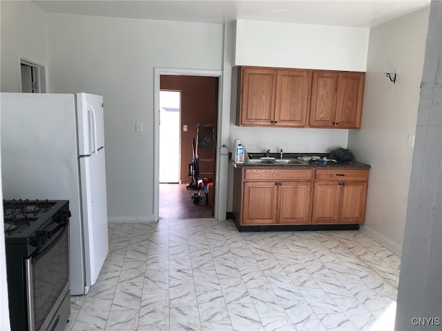 kitchen with brown cabinetry, dark countertops, stainless steel gas range, marble finish floor, and a sink