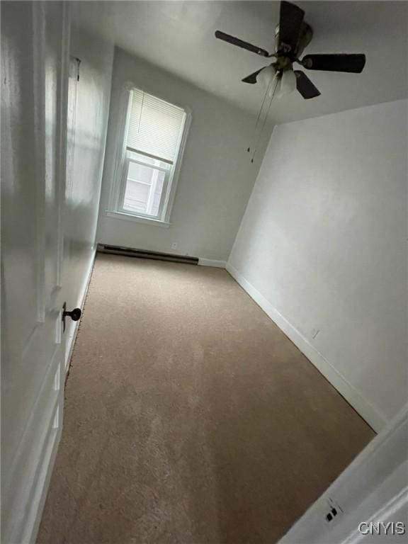 empty room with baseboards, a baseboard heating unit, a ceiling fan, and light colored carpet