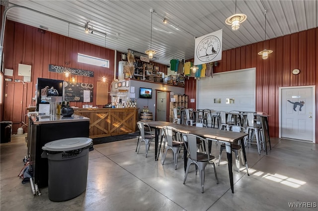 kitchen featuring concrete flooring, decorative light fixtures, and wooden walls