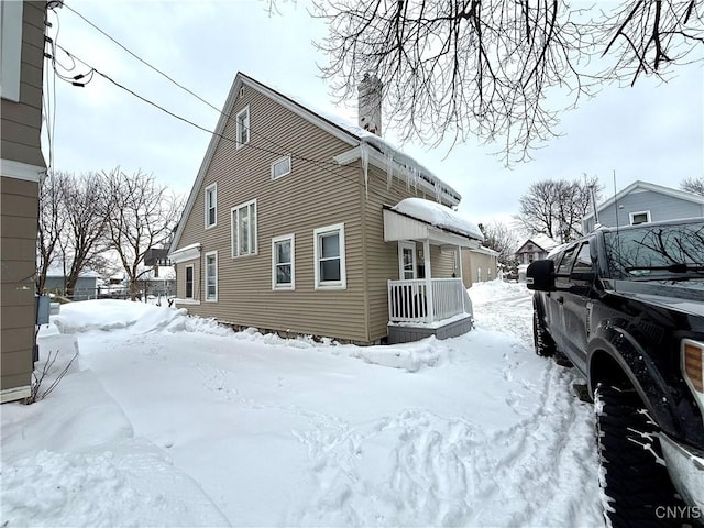 view of snow covered exterior with a chimney