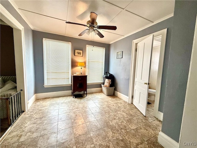 interior space featuring baseboards, ceiling fan, and crown molding