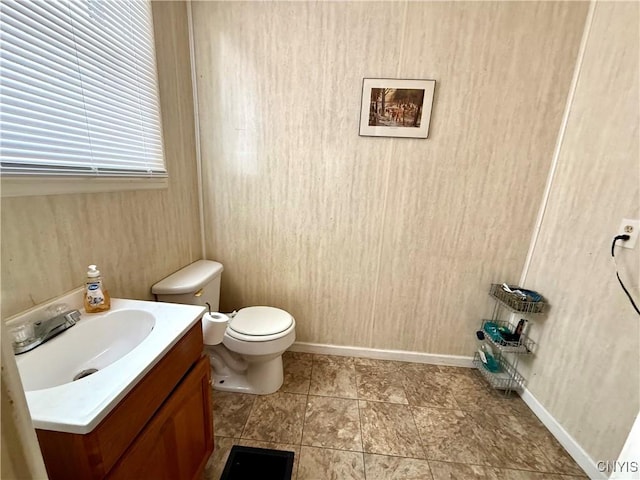 half bathroom featuring toilet, vanity, and baseboards