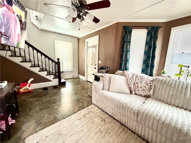 living area with ceiling fan, stairway, baseboards, and crown molding