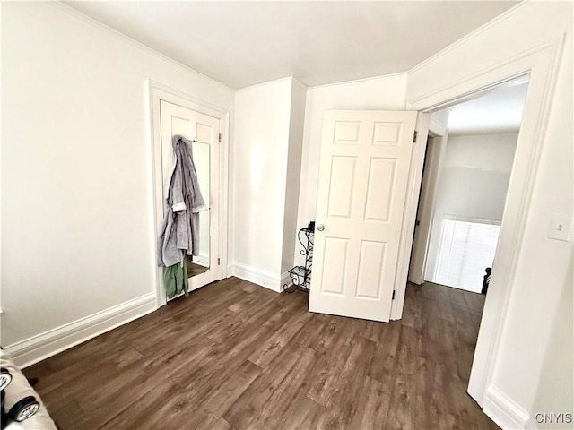 unfurnished bedroom with crown molding, dark wood finished floors, and baseboards