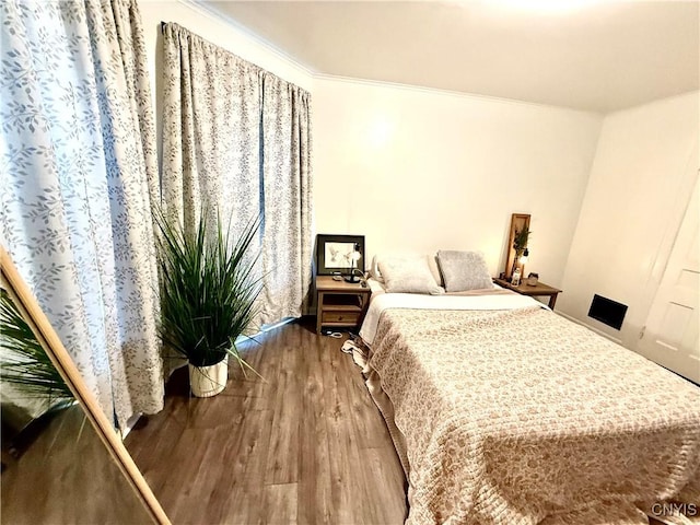 bedroom with ornamental molding and wood finished floors