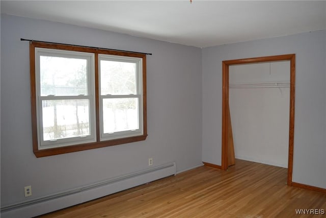 unfurnished bedroom with baseboards, light wood-style flooring, a baseboard heating unit, and a closet