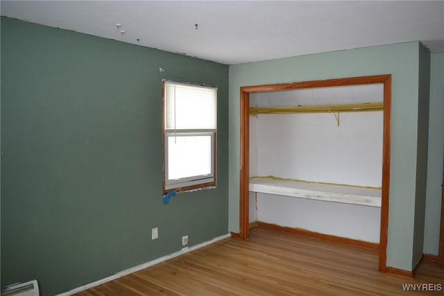 unfurnished bedroom with a closet, baseboards, and light wood finished floors