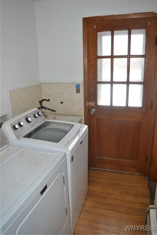 laundry room with laundry area, wainscoting, wood finished floors, washer and dryer, and tile walls