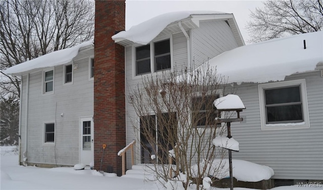 view of snowy exterior featuring a chimney