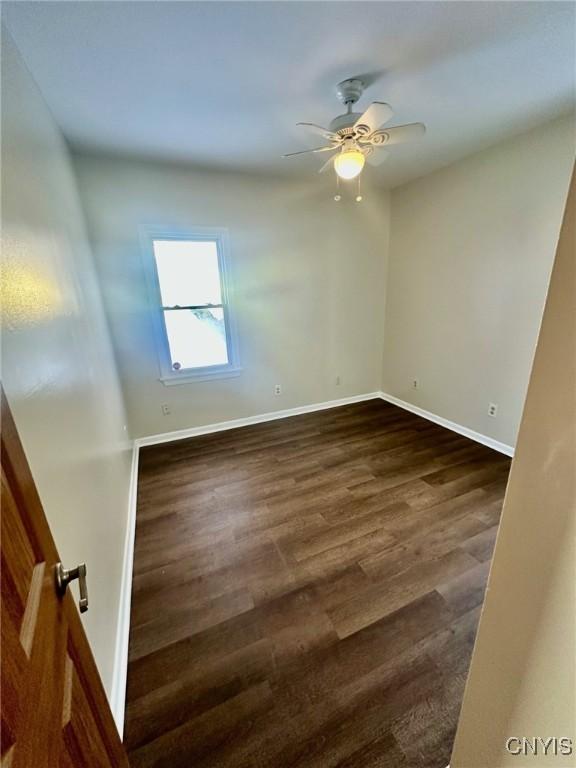 unfurnished room featuring dark wood-style floors, ceiling fan, and baseboards