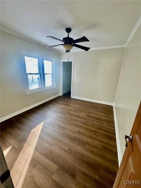 unfurnished bedroom featuring baseboards, dark wood-style flooring, and crown molding