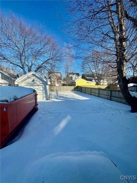 yard layered in snow with an outdoor structure and fence