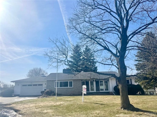 ranch-style home featuring an attached garage, concrete driveway, and a front lawn