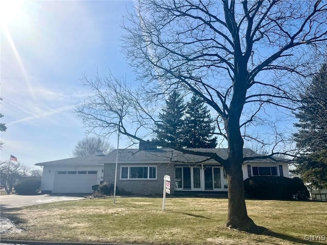 single story home featuring a garage, driveway, brick siding, and a front yard