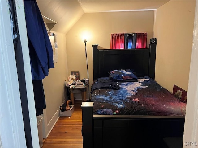 bedroom featuring light wood finished floors and vaulted ceiling