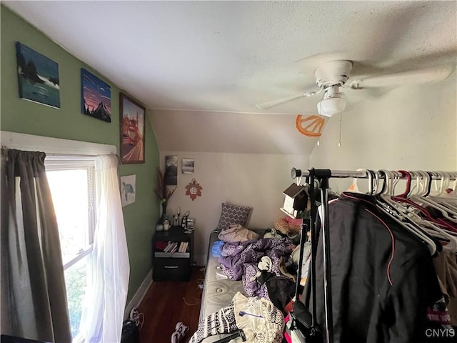 bedroom featuring baseboards, lofted ceiling, ceiling fan, wood finished floors, and a textured ceiling