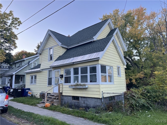 view of front of property featuring entry steps, roof with shingles, and metal roof