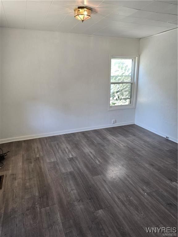 unfurnished room featuring baseboards and dark wood-type flooring