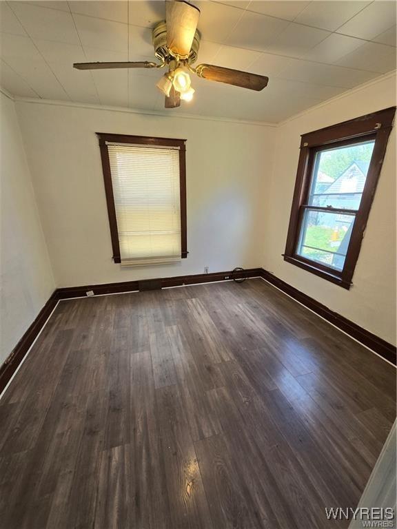 spare room with ceiling fan, baseboards, and dark wood-type flooring