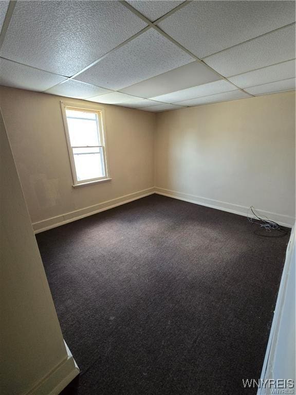 spare room featuring a paneled ceiling, baseboards, and carpet flooring