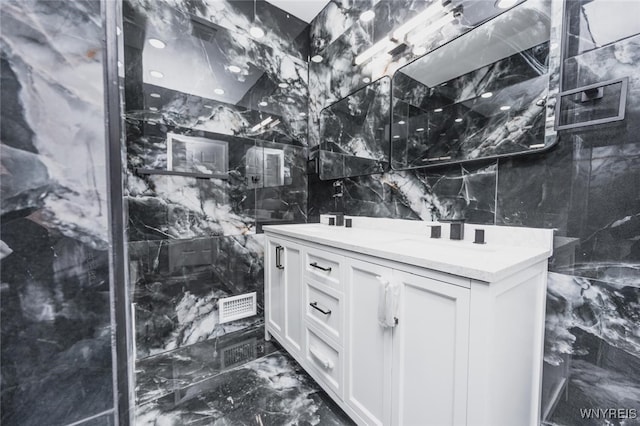 bathroom featuring marble finish floor, tile walls, double vanity, visible vents, and a sink