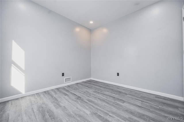 empty room with recessed lighting, wood finished floors, visible vents, and baseboards