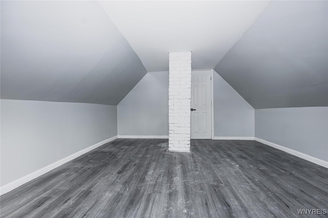 additional living space featuring dark wood-style floors, vaulted ceiling, and baseboards