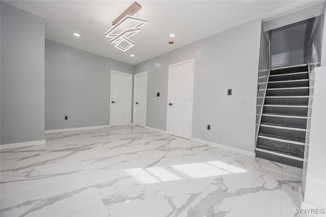 unfurnished room with recessed lighting, marble finish floor, baseboards, and stairs