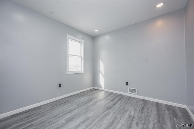 empty room featuring visible vents, baseboards, wood finished floors, and recessed lighting