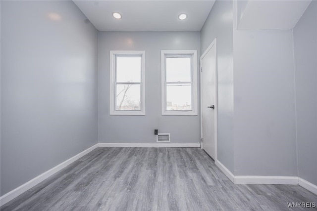 unfurnished room with light wood finished floors, baseboards, and visible vents