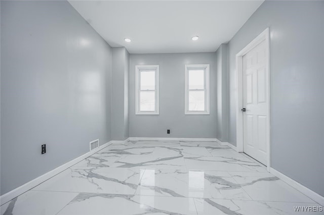 empty room with marble finish floor, visible vents, and baseboards