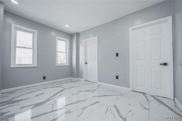 empty room featuring marble finish floor, recessed lighting, and baseboards