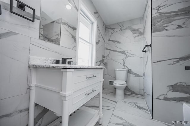 full bathroom with marble finish floor, vanity, toilet, and stone wall