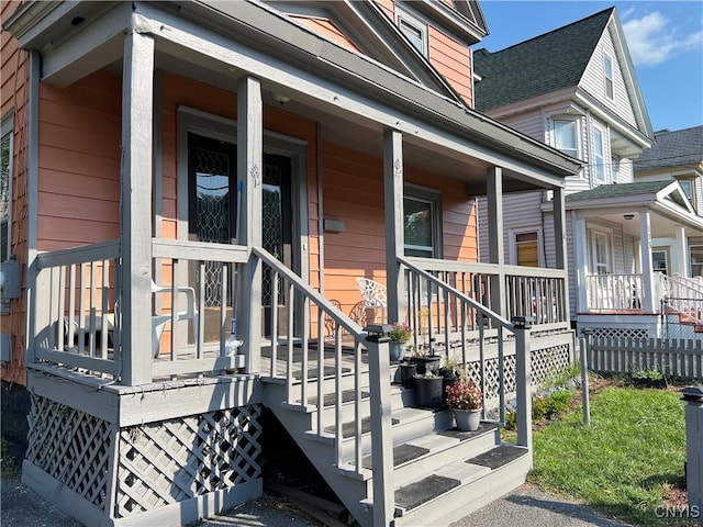 view of exterior entry featuring covered porch and roof with shingles