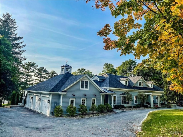 view of front of home with aphalt driveway, roof with shingles, and an attached garage