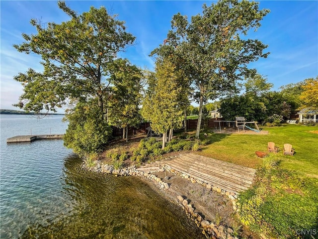 exterior space featuring a water view, a playground, and a lawn