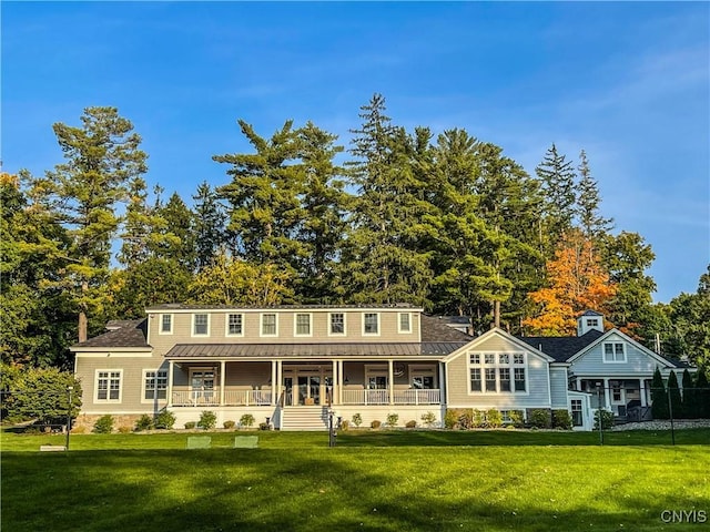 view of front facade featuring covered porch, metal roof, a front lawn, and a standing seam roof