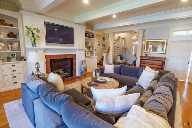 living area with stairs, light wood finished floors, beamed ceiling, and ornamental molding