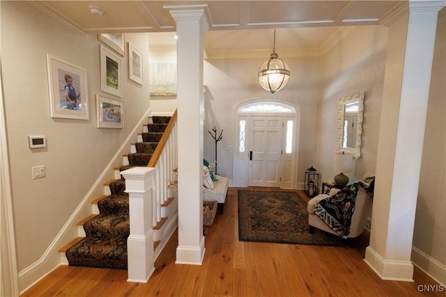 entryway featuring crown molding, baseboards, stairway, light wood-type flooring, and ornate columns