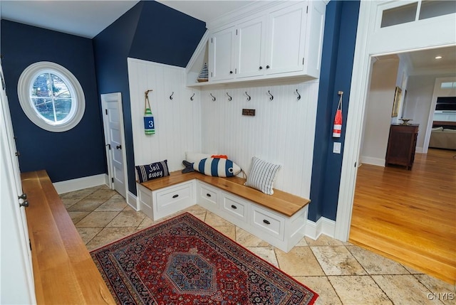 mudroom with stone tile floors and baseboards