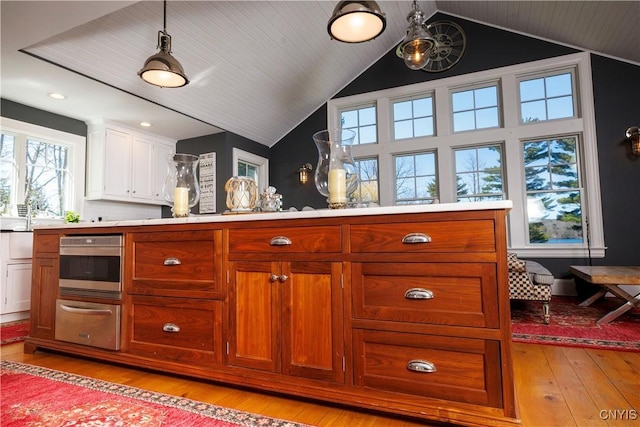 kitchen with light wood finished floors, oven, vaulted ceiling, light countertops, and a warming drawer