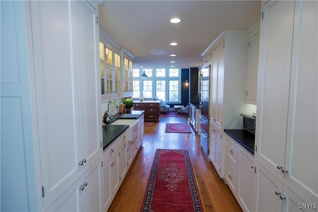 interior space featuring recessed lighting, dark countertops, wood finished floors, and white cabinets