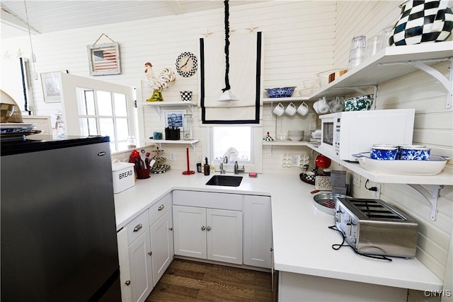 kitchen with white microwave, light countertops, a sink, and decorative light fixtures