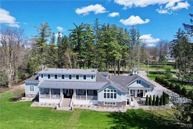 back of property with a sunroom, a lawn, stairway, and metal roof