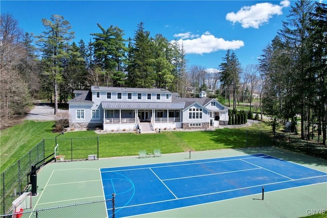 view of tennis court with basketball court, fence, and a lawn