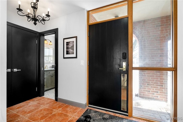 foyer featuring light tile patterned floors, a notable chandelier, and baseboards