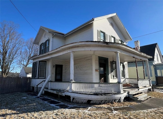 farmhouse with a porch and fence