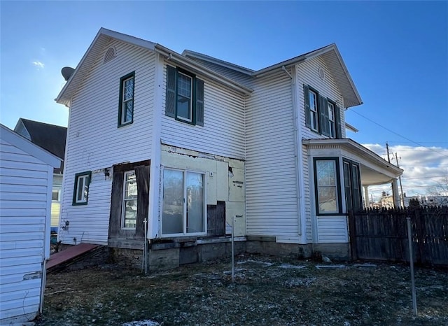 rear view of house featuring entry steps and fence