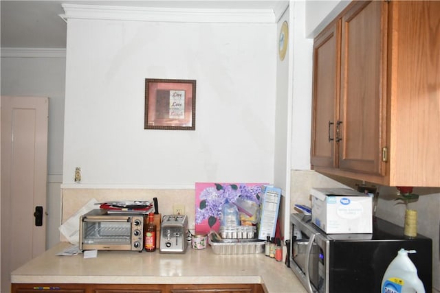 kitchen with light countertops, ornamental molding, and brown cabinets