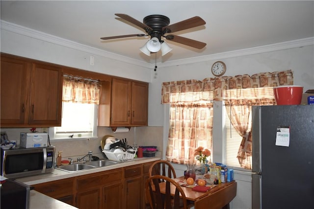 kitchen featuring brown cabinets, stainless steel appliances, light countertops, ornamental molding, and a sink